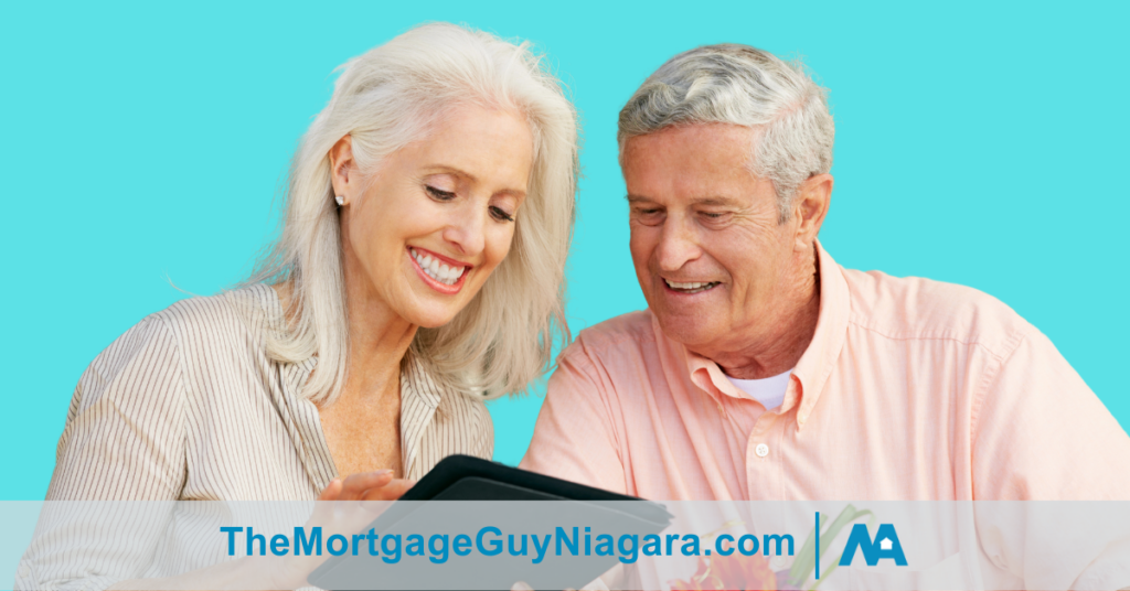 senior couple smiling looking at a tablet with a teal coloured background